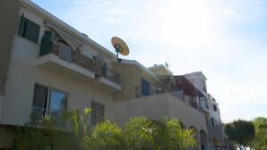 A multi-story building with balconies, satellite dishes, and a clear sky. - Sunrise Studios (Limassol)
