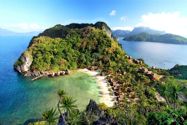 A tropical island with a beach, clear waters, and lush greenery. - Cauayan Boutique Private Island (El Nido)