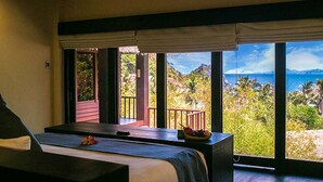Una habitación con una cama, una mesa de masajes y vistas al océano y las colinas.