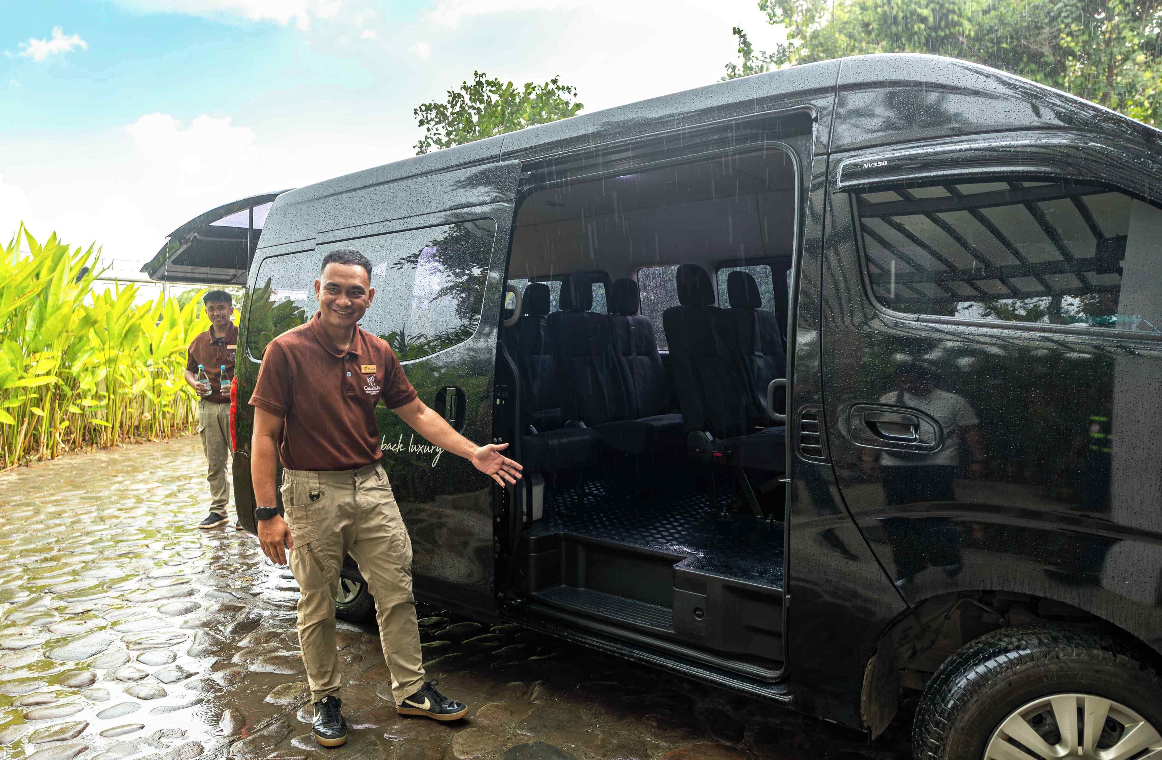 A black van with a partially open door, a person standing next to it, and a cobblestone path.