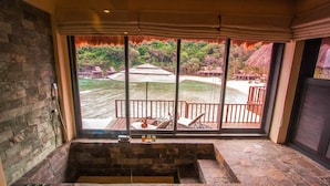 A stone bathtub with a view of a deck and beach. - Cauayan Boutique Private Island (El Nido)
