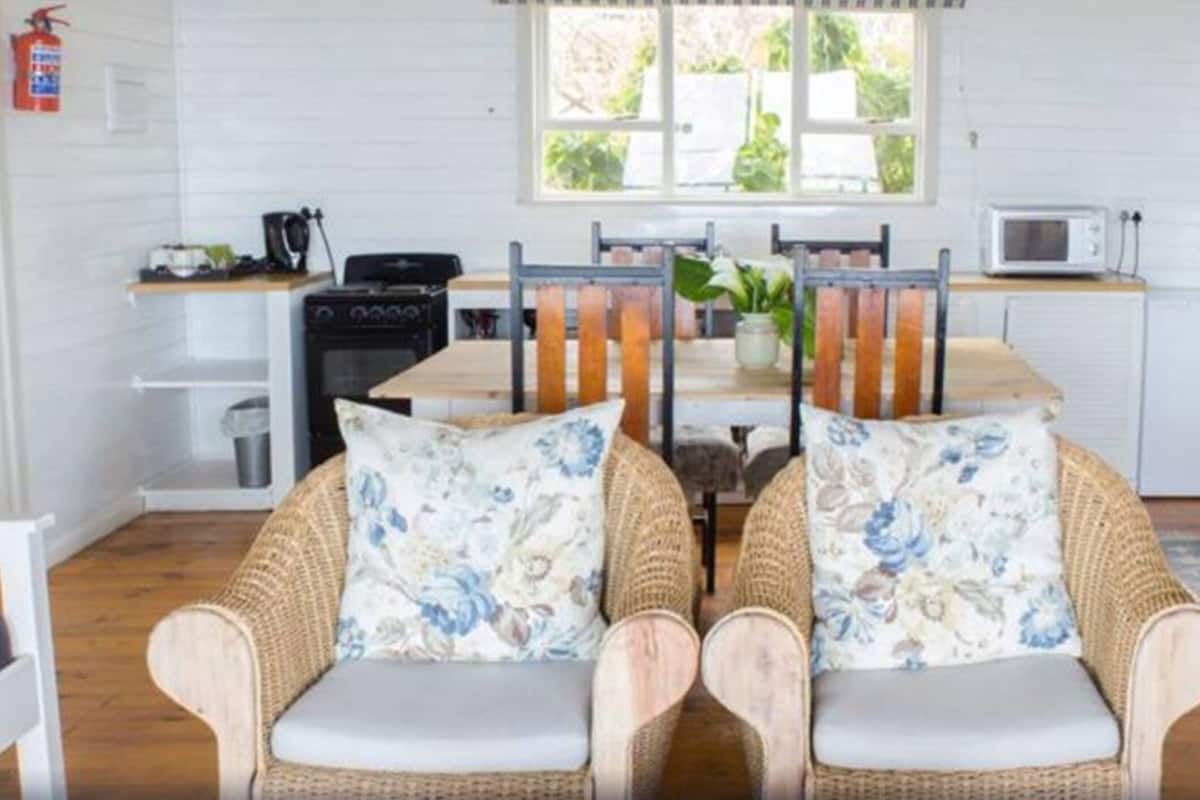 A cozy room with wicker furniture, a dining table, a microwave, and a small kitchen area.