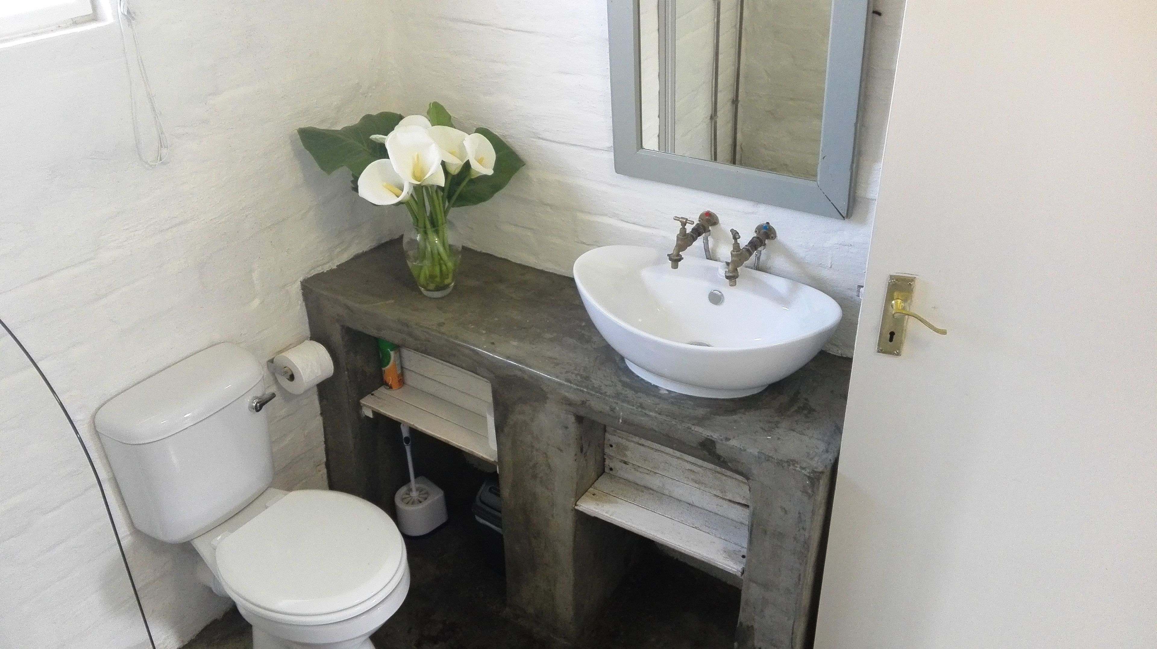 Un baño con un inodoro blanco, un lavabo blanco y un espejo sobre él.