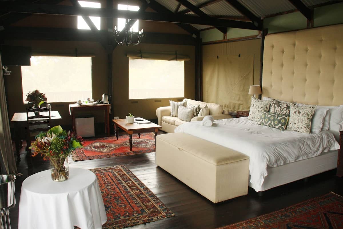 A bedroom with a bed, a sofa, a table, and a chair.