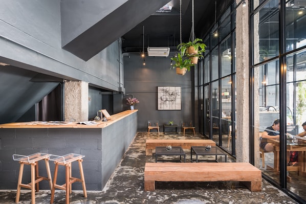 Un café moderno con barra, taburetes y mesas de madera.