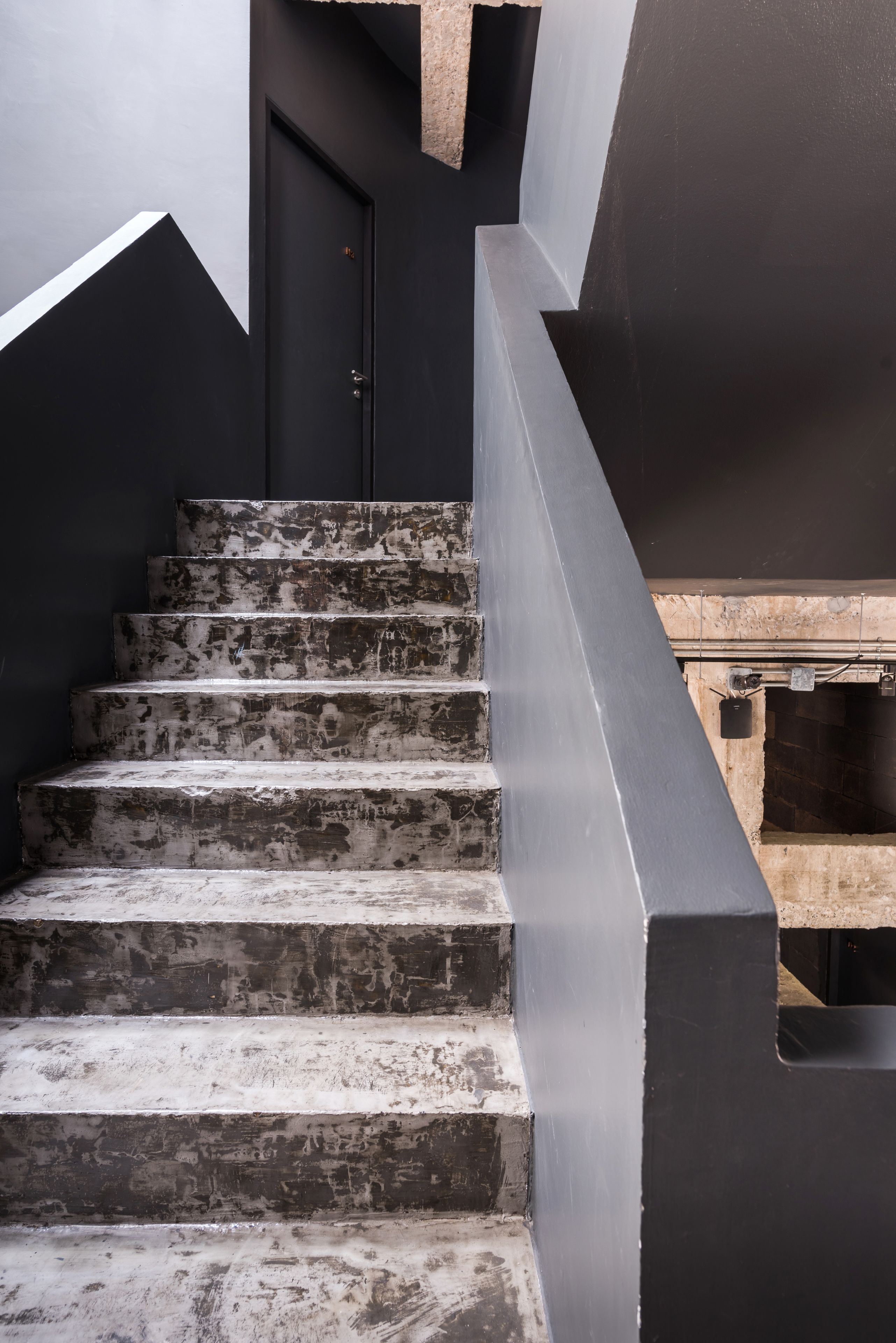 A staircase with a black handrail and a door at the top.