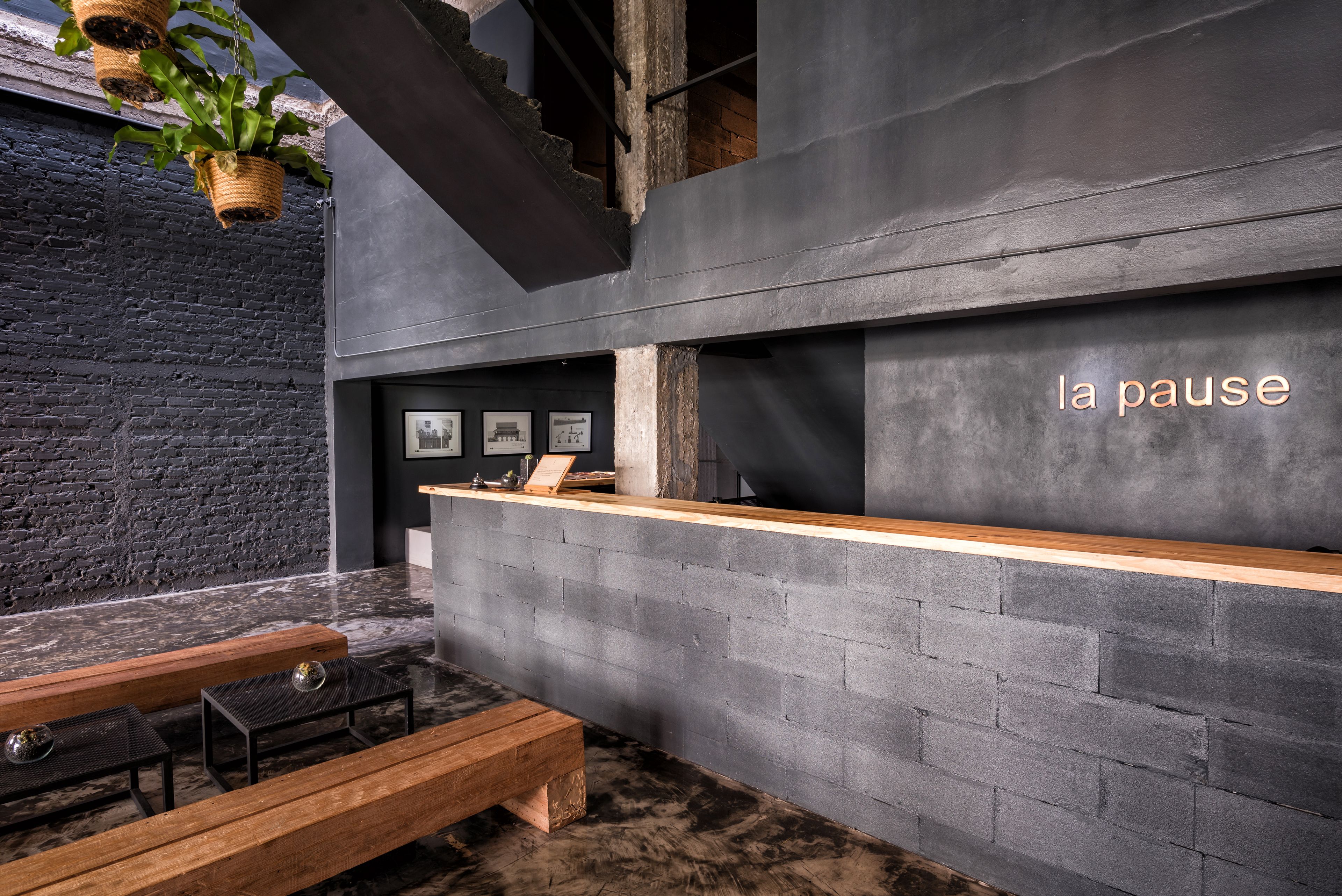A modern interior with a reception desk, wooden benches, and a black brick wall.