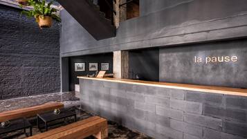 A modern interior with a reception desk, wooden benches, and a black brick wall.