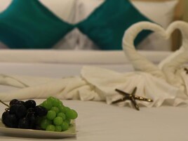 Una cama con ropa blanca y una almohada con forma de corazón.