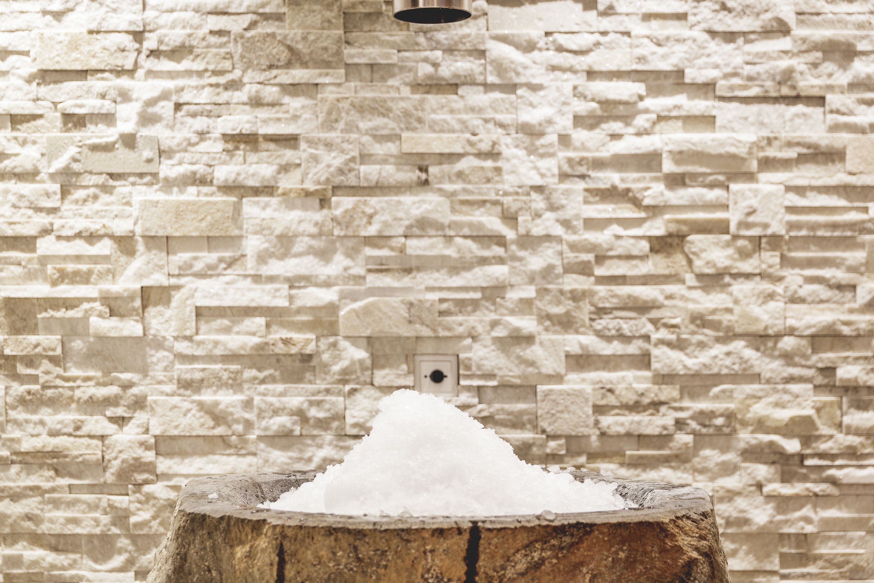 A stone wall with a pile of salt in front of it.