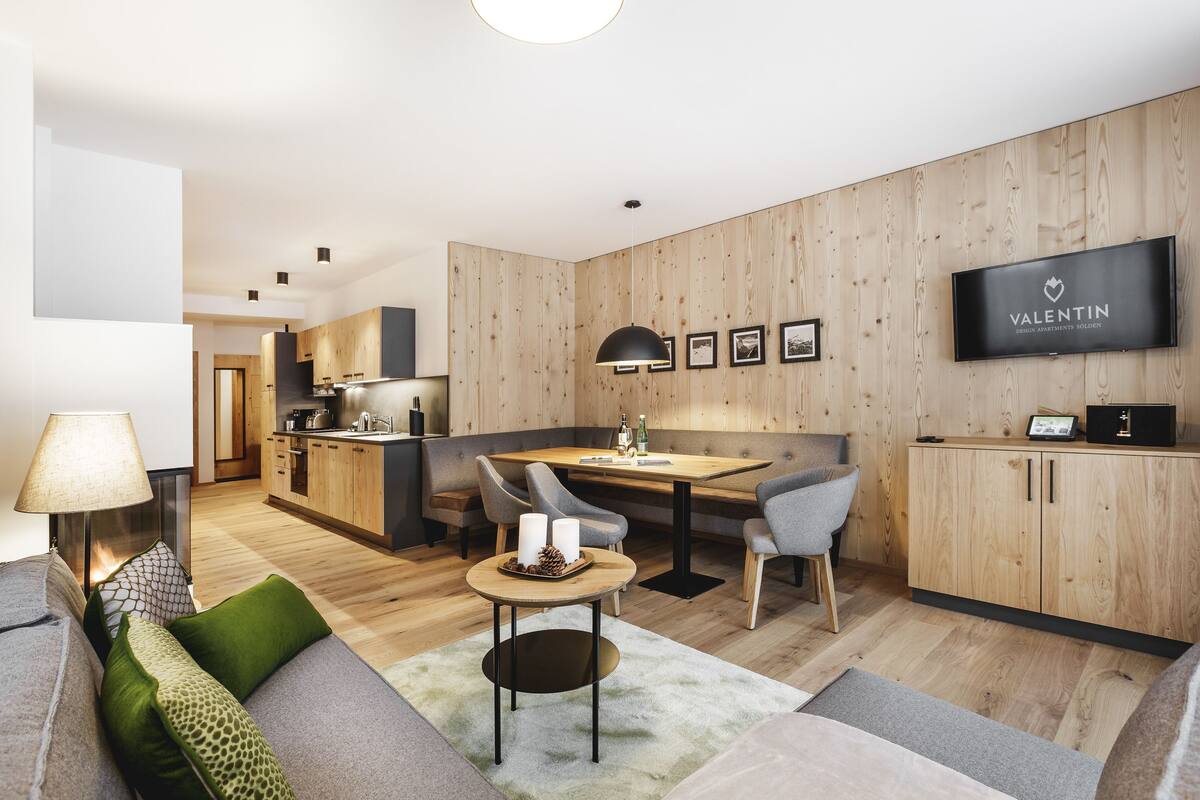 Una sala de estar moderna con un sofá, una mesa de comedor y un televisor montado en la pared.