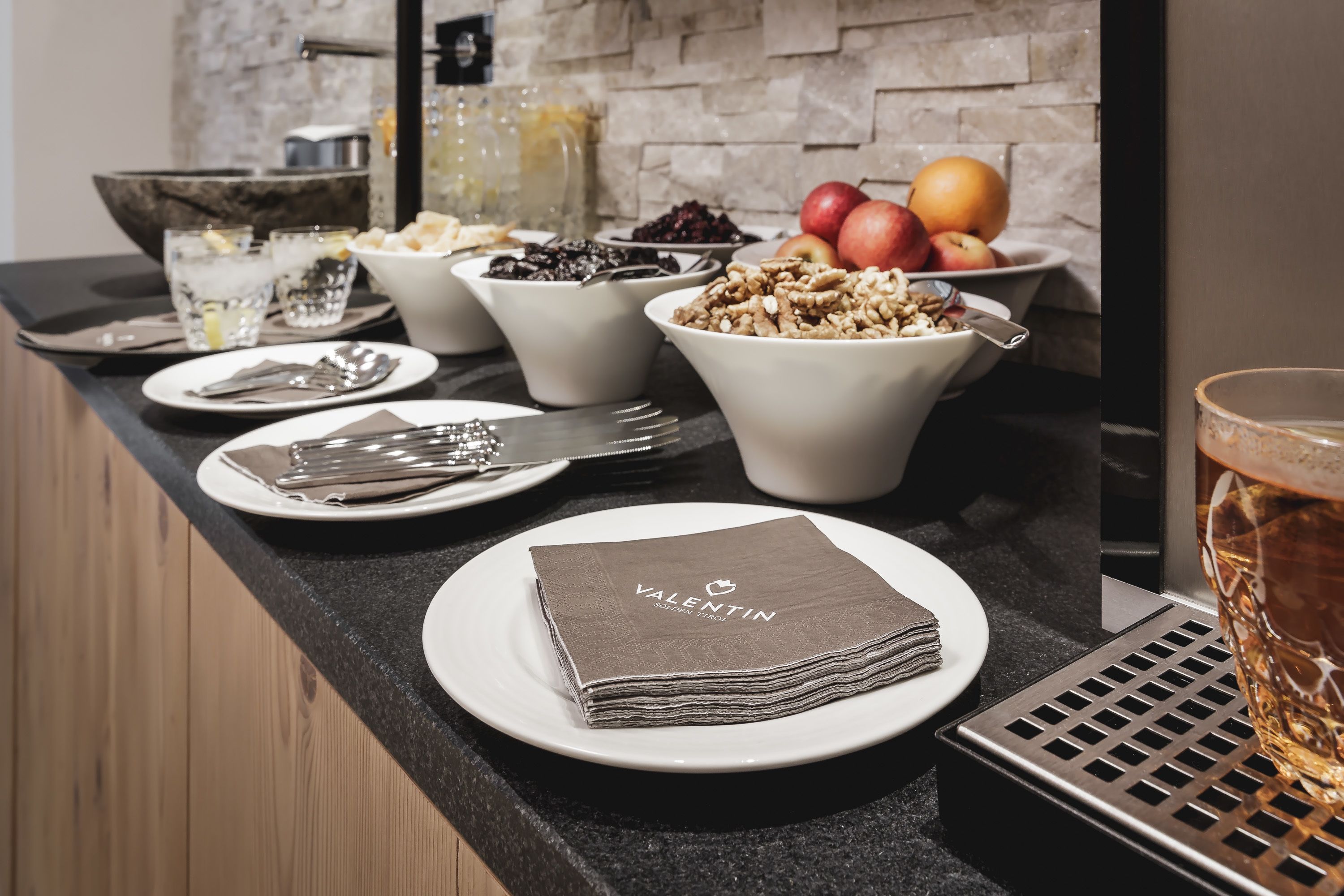 A breakfast setup with bowls of cereal, fruits, and a folded napkin on a plate.