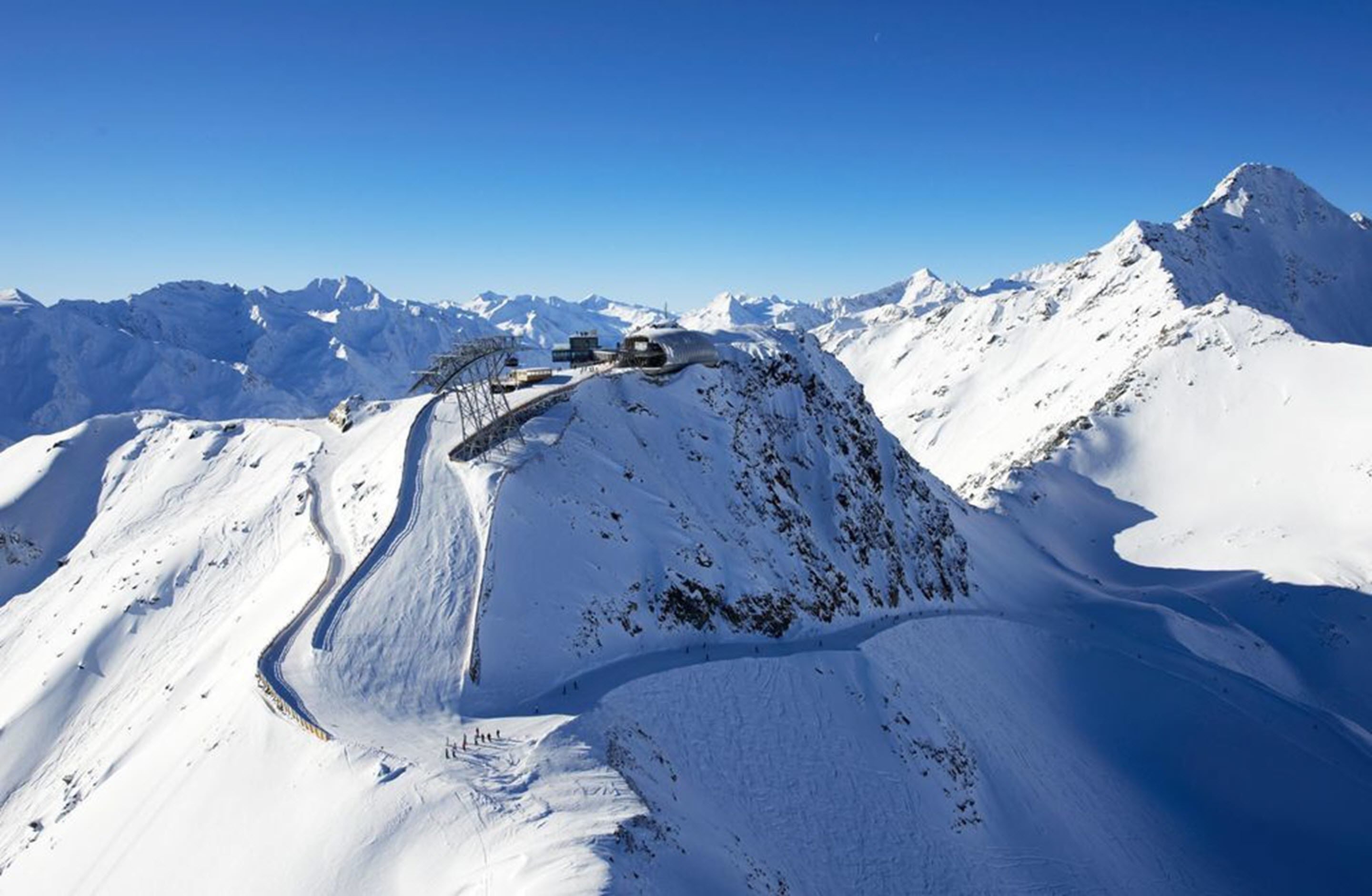 A snow-covered mountain with a ski lift and a clear sky.
