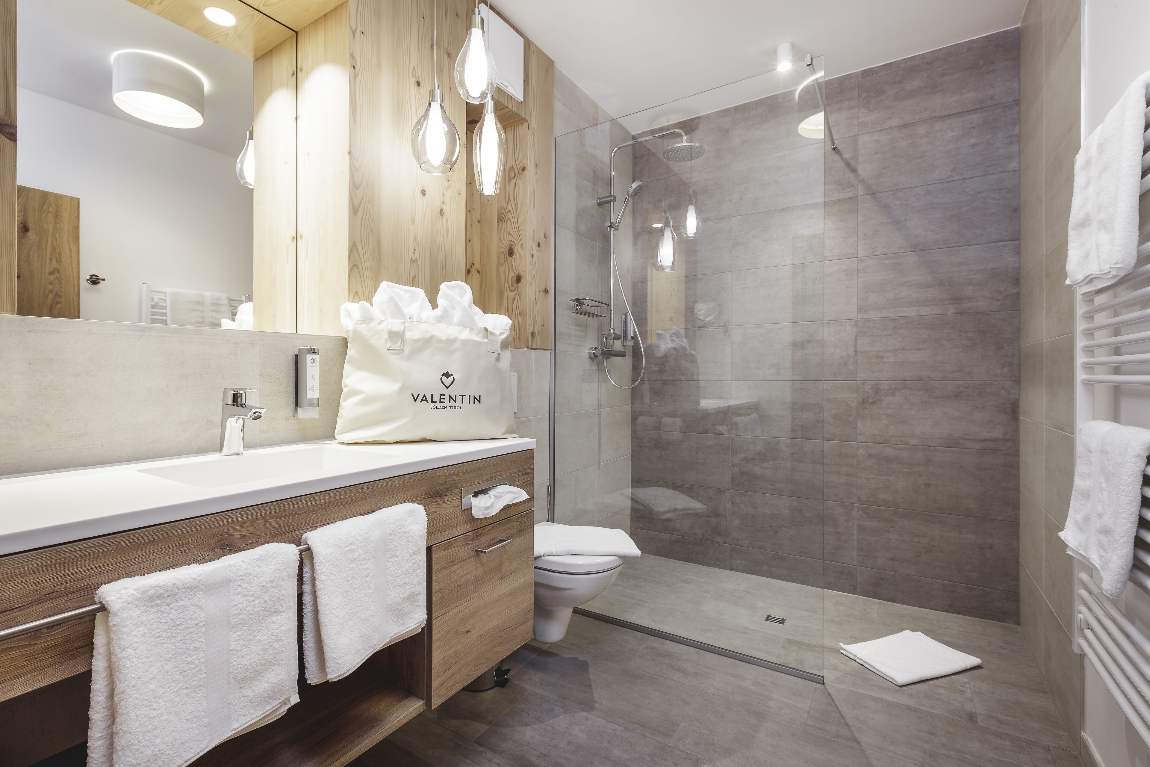 A modern bathroom with a wooden vanity, a glass shower enclosure, and a white toilet.