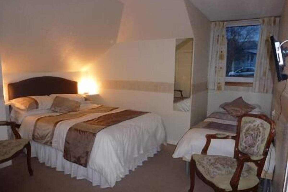 A hotel room with a bed, a chair, a desk, and a television.