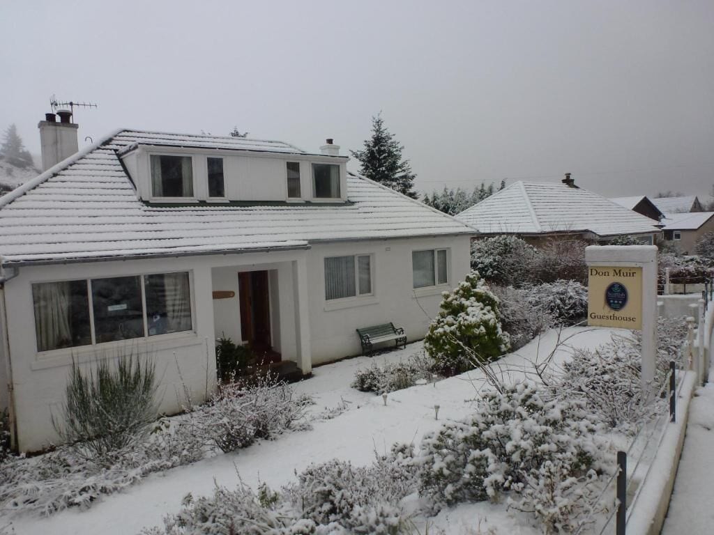 A snow-covered building with a sign indicating it is a guesthouse.