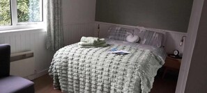 A bedroom with a bed, a chair, a window, and a radiator. - Don Muir Guest House (Oban)