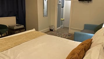 A hotel room with a bed, a chair, a television, and a small table.