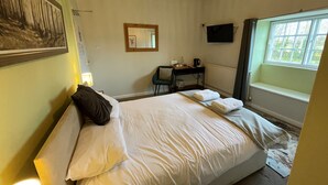 Una habitación de hotel con una cama, un escritorio, una silla, un televisor y una ventana.