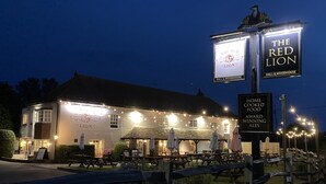Un pub llamado "The Red Lion" con terraza y letrero iluminado.