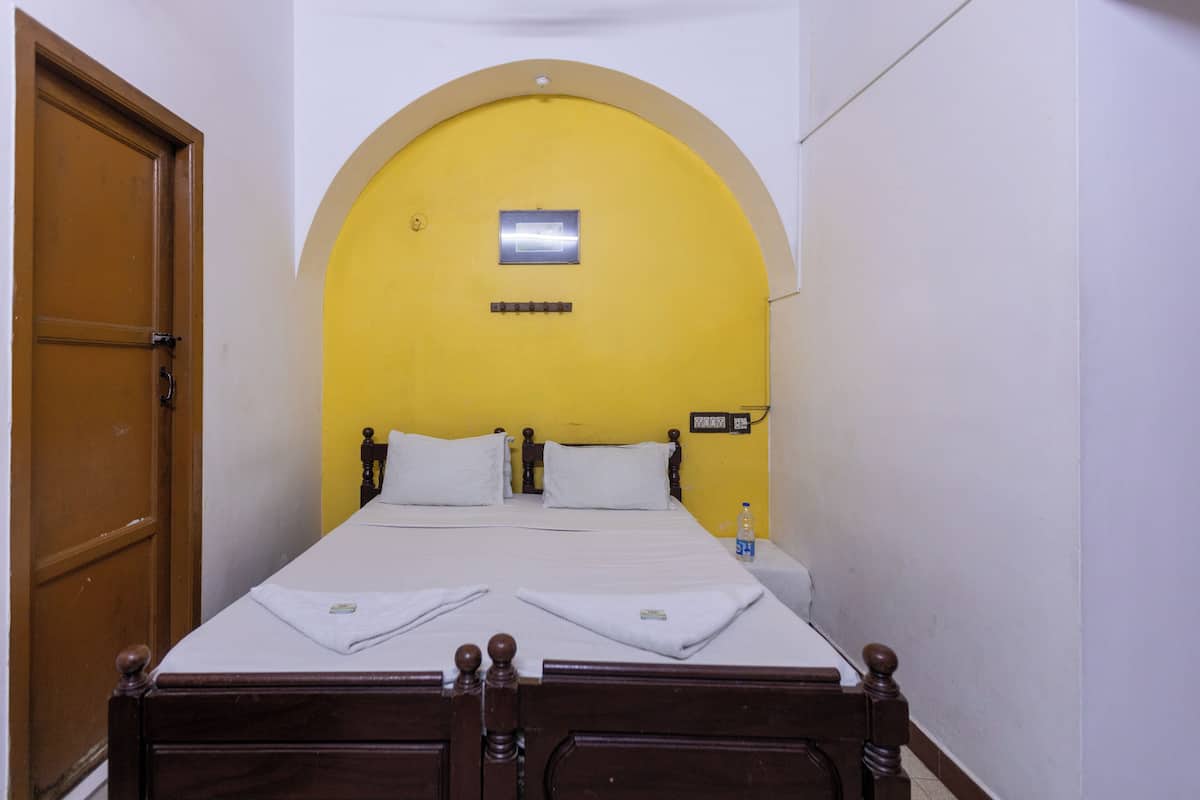 A room with a bed, a wooden door, and a yellow wall.