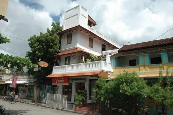 A two-story building with a balcony on the upper floor, a signboard, and a staircase leading to the entrance. - Hotel Coramandal Heritage (Puducherry)