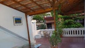 Un espacio al aire libre con un porche de madera, un banco blanco y una planta en maceta.