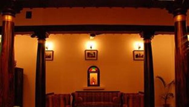 Una habitación cálidamente iluminada con un sofá, cuadros en la pared y una chimenea.