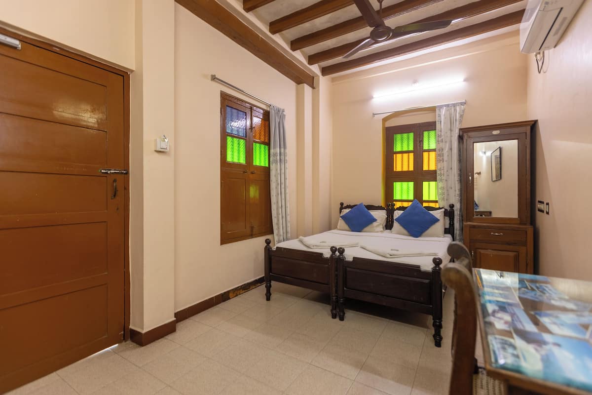 A bedroom with a wooden bed, a nightstand, a mirror, and a window with curtains.
