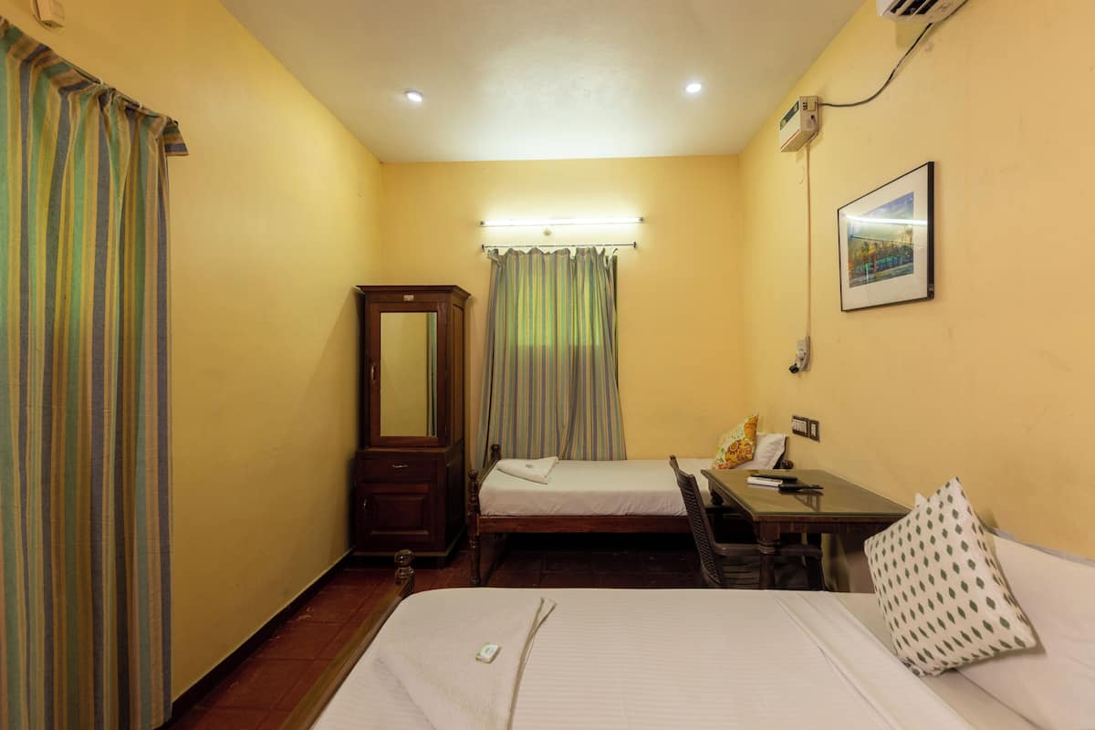 A hotel room with a bed, a desk, a chair, a mirror, and a window with curtains.