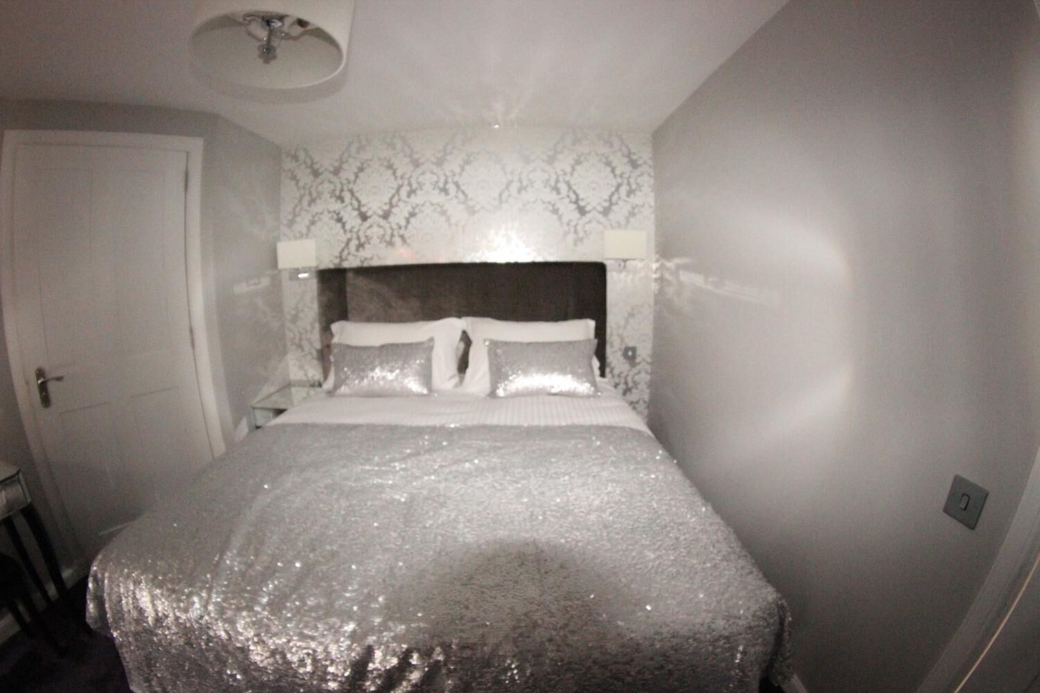 A bedroom with a bed, a headboard, a door, and a wall with a patterned design.
