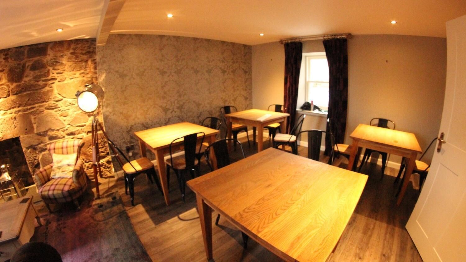 Un comedor acogedor con pared de piedra, mesas y sillas de madera.