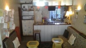 A compact living space with a kitchenette, a sofa, and two yellow stools.