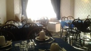 A dining area with tables set for two, featuring dark blue tablecloths and matching chairs.