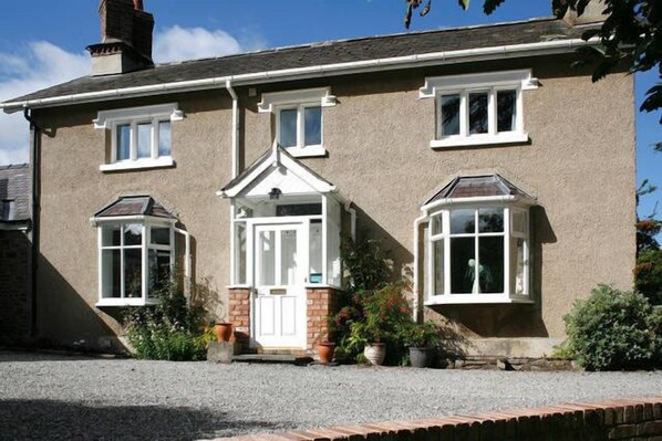 A two-story house with a symmetrical facade, a central entrance with a white door, and a small porch with a white railing. - The Old Rectory Bed & Breakfast (Ruthin)