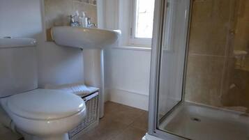 Un baño con inodoro, lavabo y ducha.