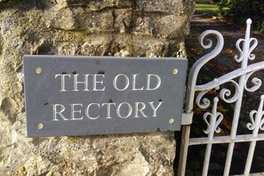 A sign reading "THE OLD RECTORY" mounted on a stone wall with a metal gate nearby. - The Old Rectory Bed & Breakfast (Ruthin)