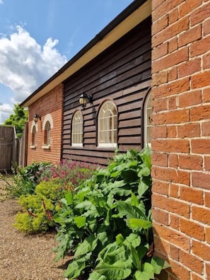 A brick house with a wooden exterior and arched windows. - The Coach House (Cranbrook)