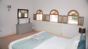 Un dormitorio con cama, cómoda, espejo y ventana con contraventanas.