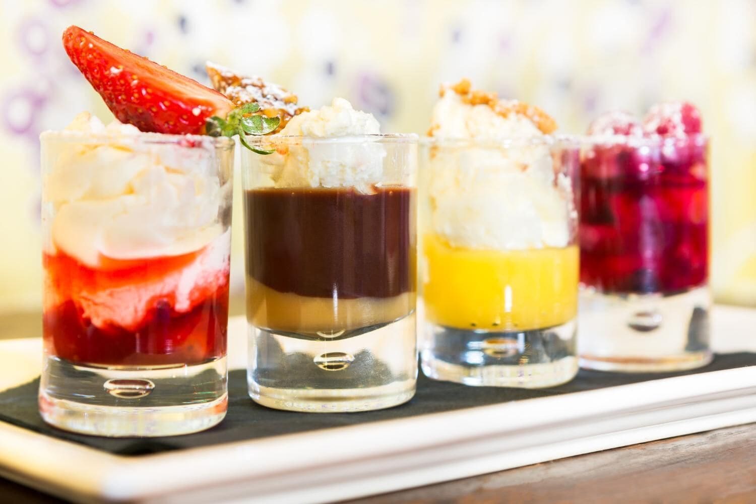 Four layered dessert drinks in clear glasses.