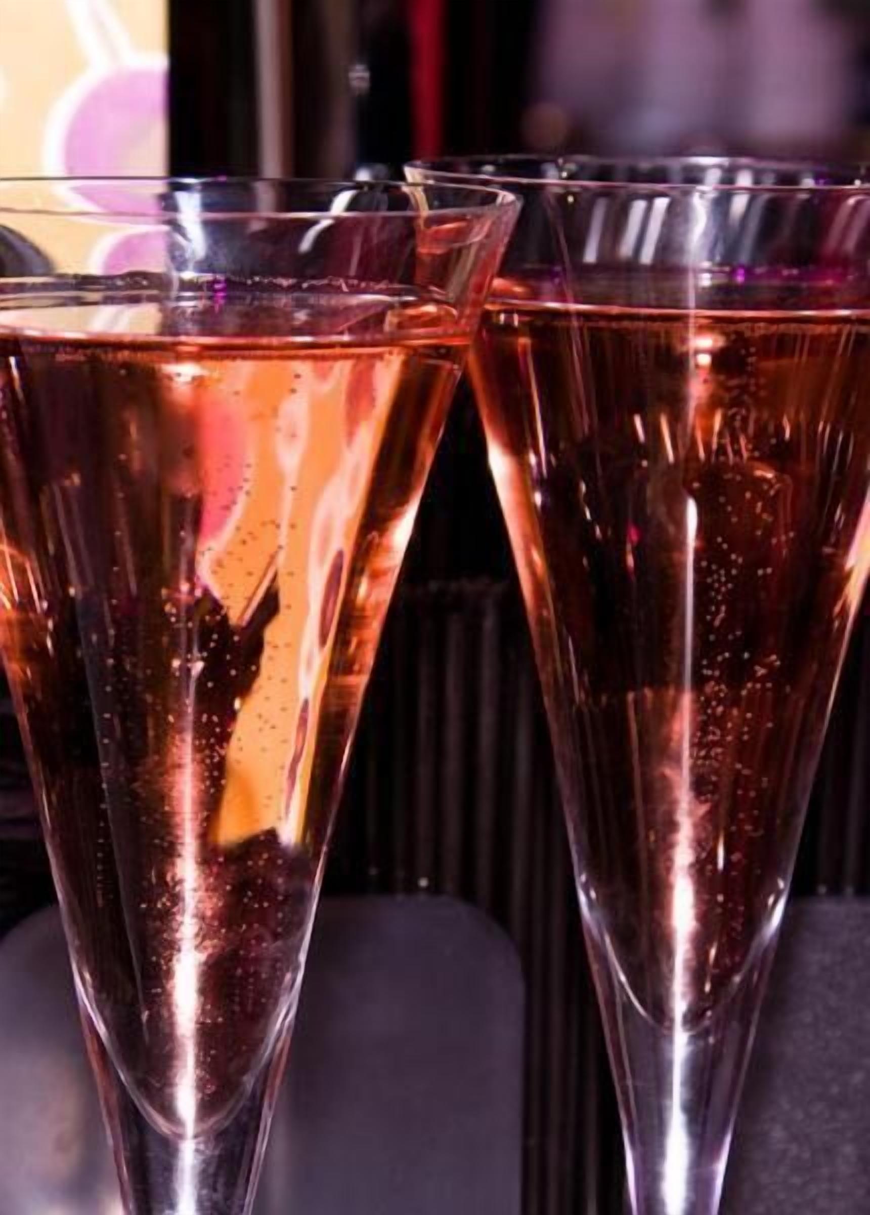 Three tall glasses filled with a bubbly beverage, likely champagne, with condensation on the outside.