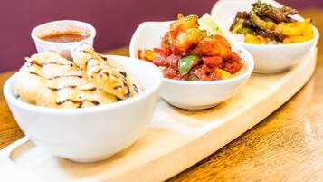 Three bowls of food on a wooden board.