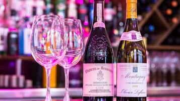 Two wine bottles and two empty wine glasses on a bar counter.