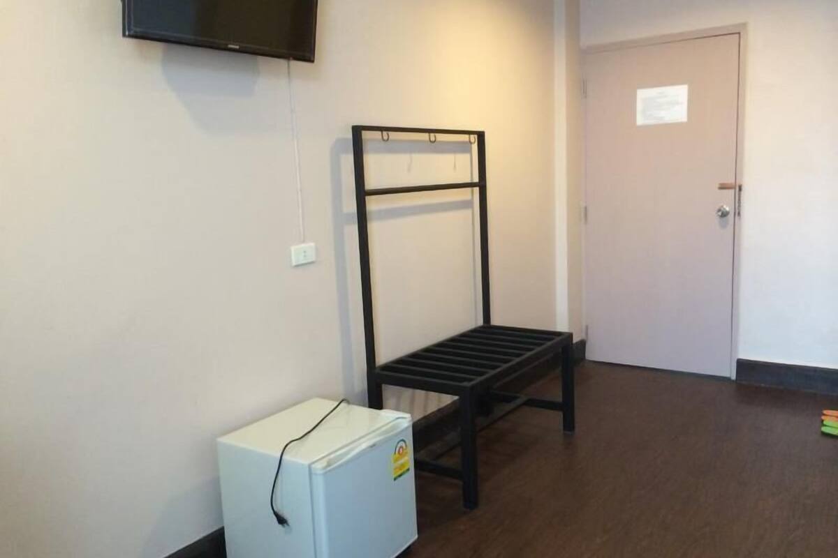Een kamer met een stapelbed, een kleine witte koelkast en een aan de muur bevestigde televisie.