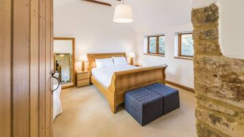 Une chambre à coucher avec un lit en bois, des lampes de chevet, un banc et une grande fenêtre.