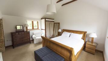 A bedroom with a wooden bed, a dresser, a bench, a nightstand, and a window with curtains.