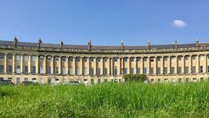 Un edificio grande e histórico con fachada simétrica, múltiples ventanas y techo plano.