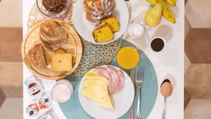 A breakfast table with various food items including bread, pastries, cheese, ham, and eggs. - Top Floor Colosseo (Rome)