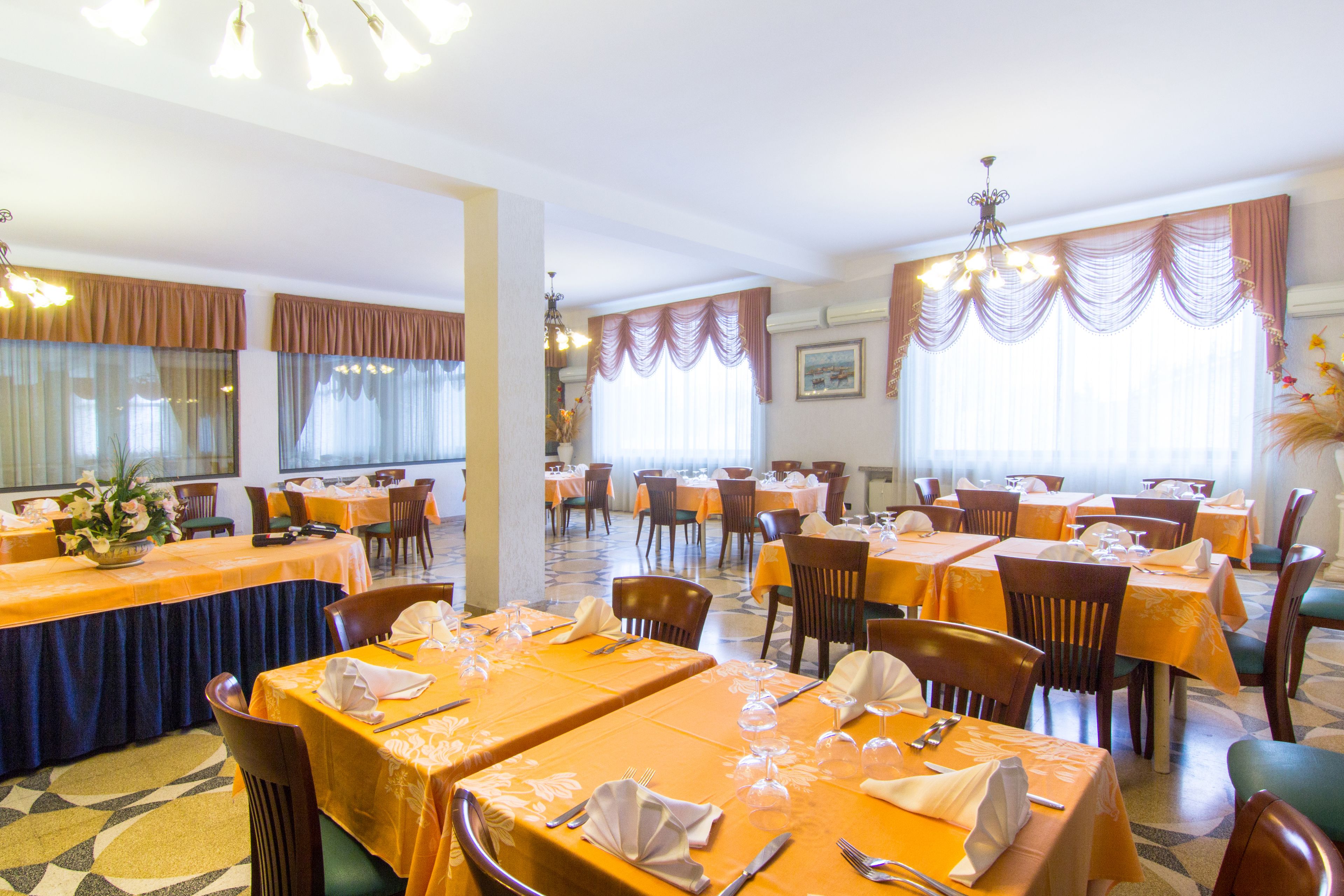 Un restaurante con varias mesas, sillas y una araña.