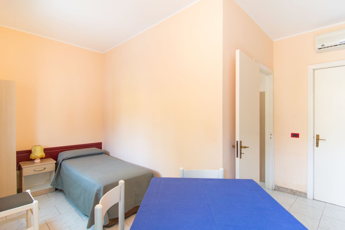 A bedroom with a bed, a desk, a chair, and a wardrobe.
